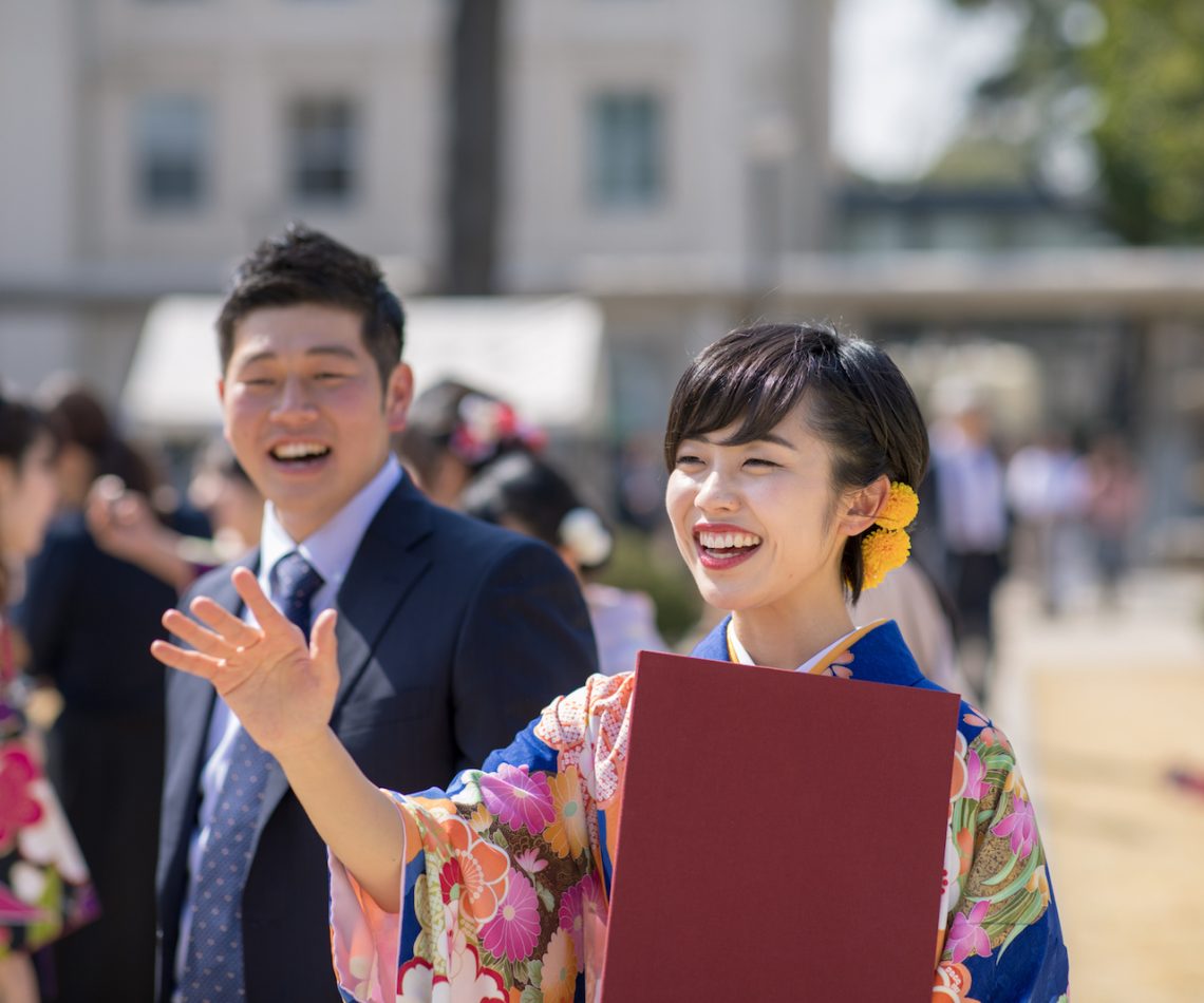 Young woman in hakama talking to frined after graduation ceremony