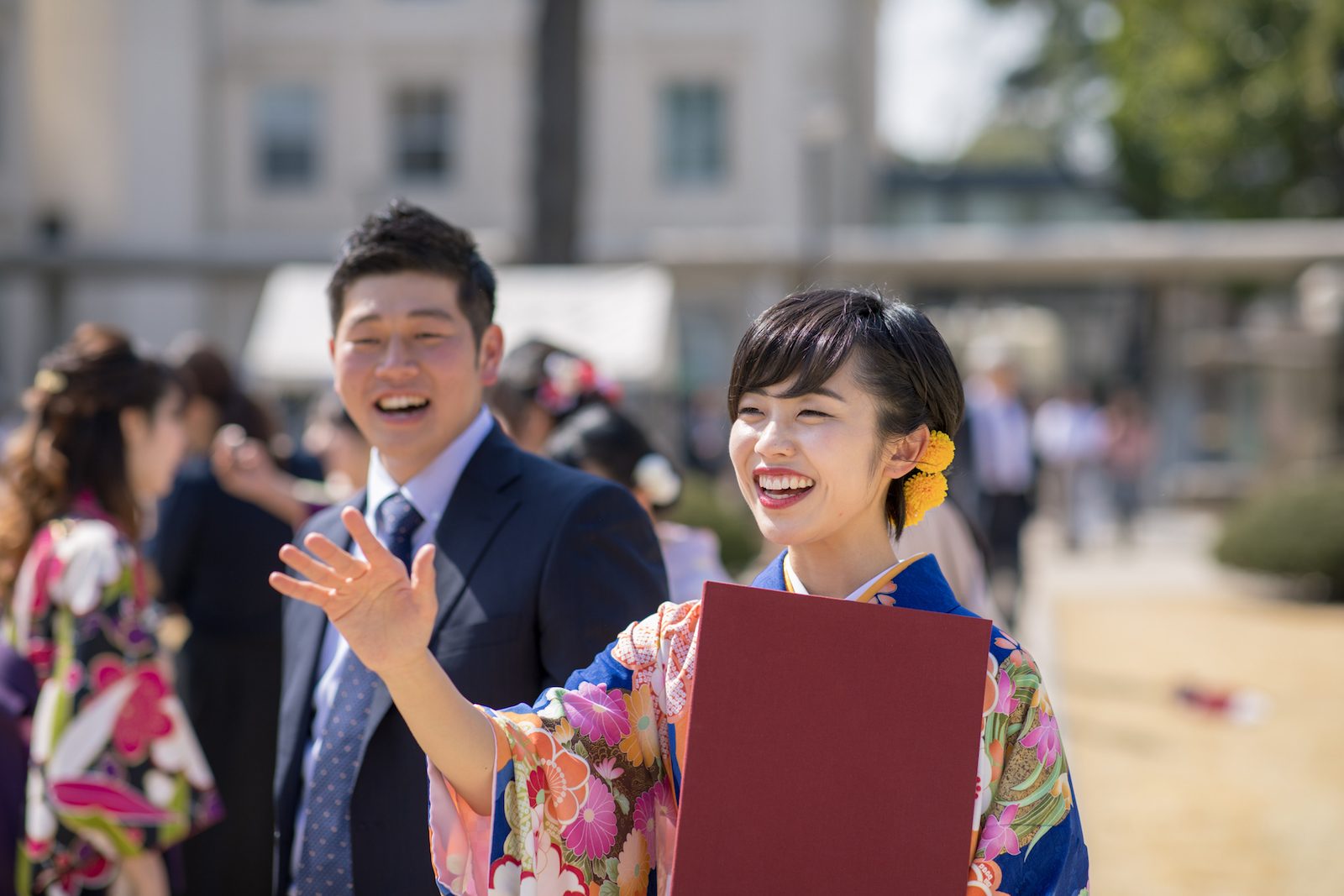 Young woman in hakama talking to frined after graduation ceremony