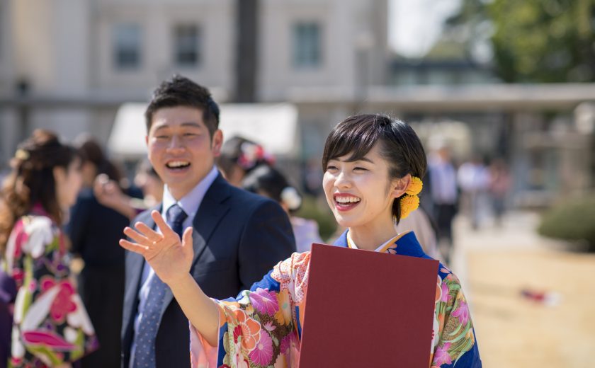 Young woman in hakama talking to frined after graduation ceremony